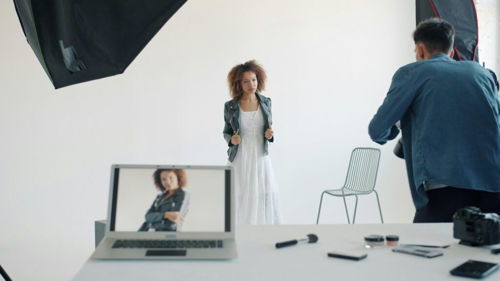 Model posiert im Studio vor Fotograf und professioneller Ausrüstung während eines Shootings