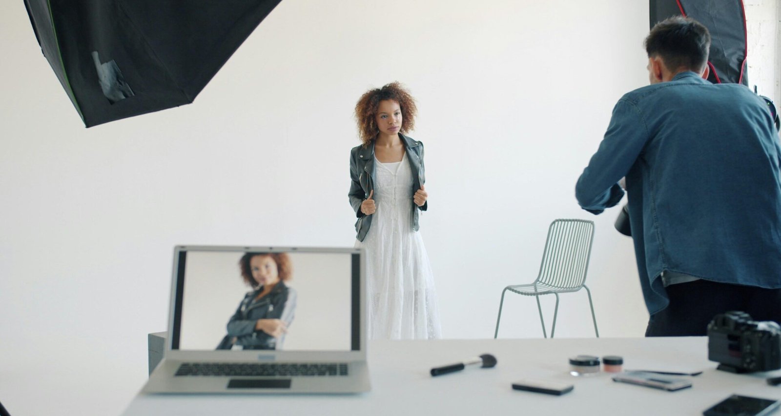 Model posiert im Studio vor Fotograf und professioneller Ausrüstung während eines Shootings