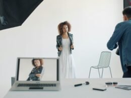 Model posiert im Studio vor Fotograf und professioneller Ausrüstung während eines Shootings