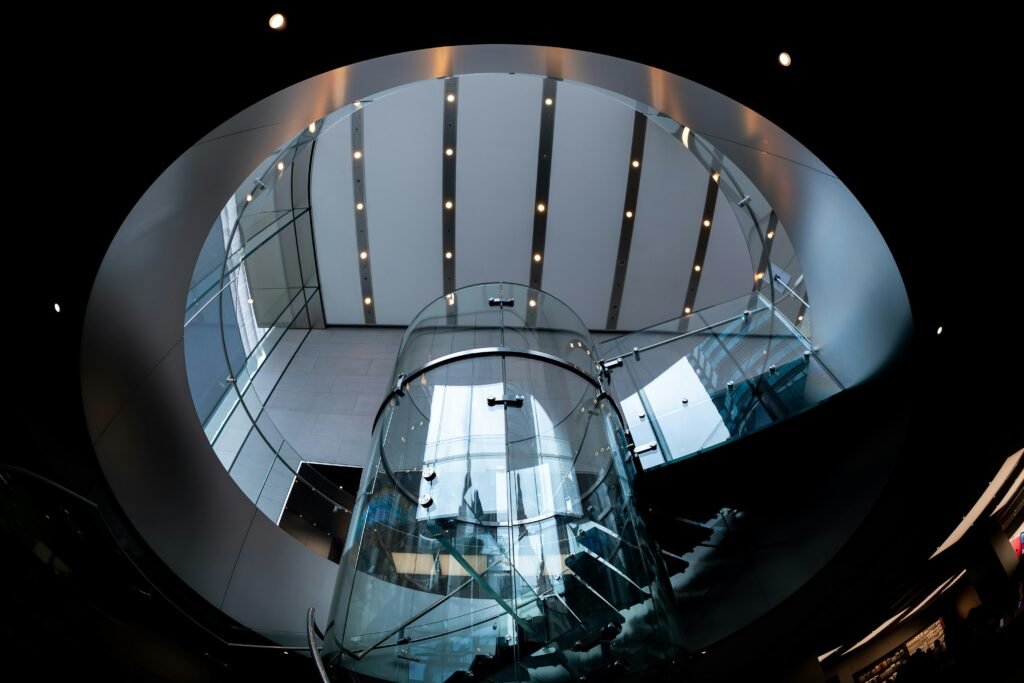 Ein Glasaufzug wird von modernen architektonischen Strukturen eingerahmt und steht im Zentrum des Bauwerks.