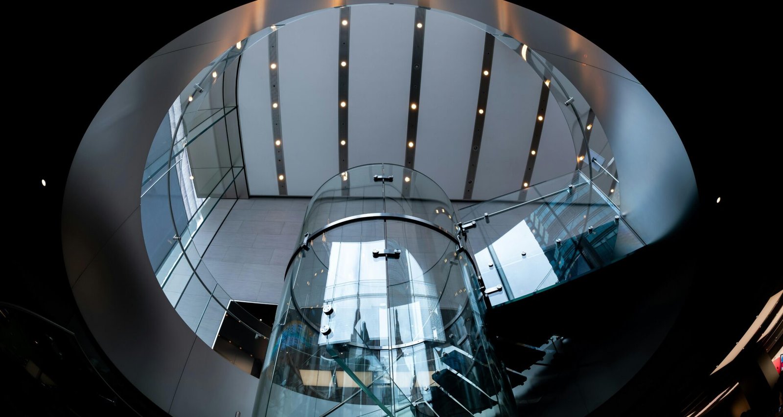 Ein Glasaufzug wird von modernen architektonischen Strukturen eingerahmt und steht im Zentrum des Bauwerks.