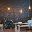 Modernes Büro mit Kreidetafelwand, Arbeitsplatz und an der Wand abgestellten Fahrrädern in einem offenen Raum