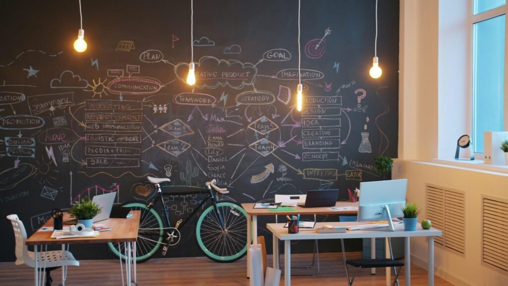 Modern eingerichtetes Büro mit einer schwarzen Tafelfläche an der Wand und abgestellten Fahrrädern im Raum.