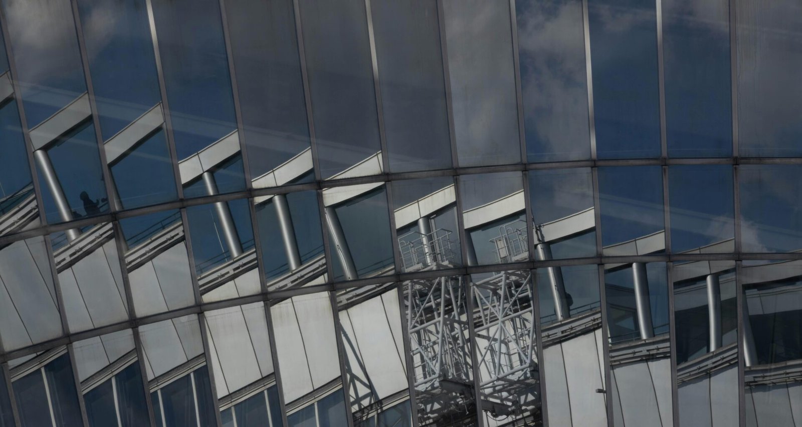 Eine moderne Fassadenansicht eines Gebäudes mit Glasfront und markanten Reflexionen städtischer Umgebung