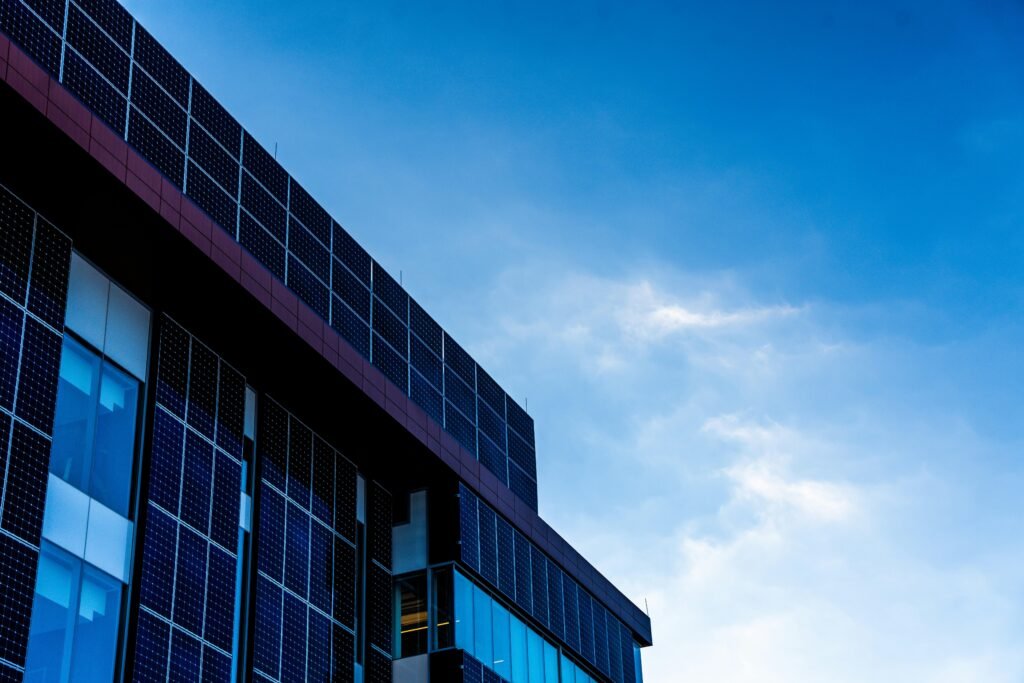 Fassade eines modernen Gebäudes mit Solarzellen, die vor einem klaren, blauen Himmel installiert sind