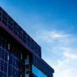 Fassade eines modernen Gebäudes mit Solarzellen, die vor einem klaren, blauen Himmel installiert sind
