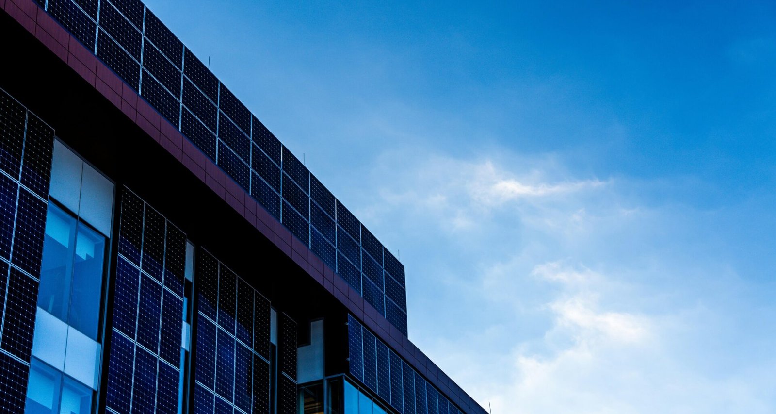Fassade eines modernen Gebäudes mit Solarzellen, die vor einem klaren, blauen Himmel installiert sind