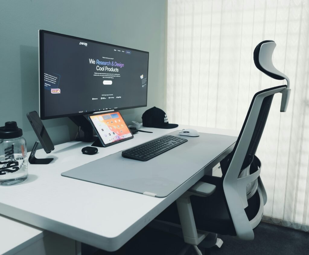 Moderner Schreibtisch mit Computer, ergonomischem Stuhl und minimalistischer Ausstattung in einem hellen Büro.