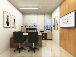 Modern eingerichtetes Büro mit mehreren Schreibtischen, ergonomischen Stühlen und Präsentationsscreen für Teammeetings
