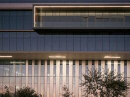 Außenansicht eines modernen Bürogebäudes bei Dämmerung mit leuchtenden Fenstern, zeitgemäße Architektur im urbanen Umfeld