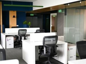 Helles Büro mit weißen Schreibtischen und schwarzen Bürostühlen, ideal für produktives Arbeiten in moderner Umgebung