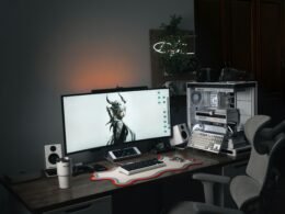 Modernes Computer-Setup mit großem Bildschirm und ergonomischem Gaming-Stuhl an einem Schreibtisch