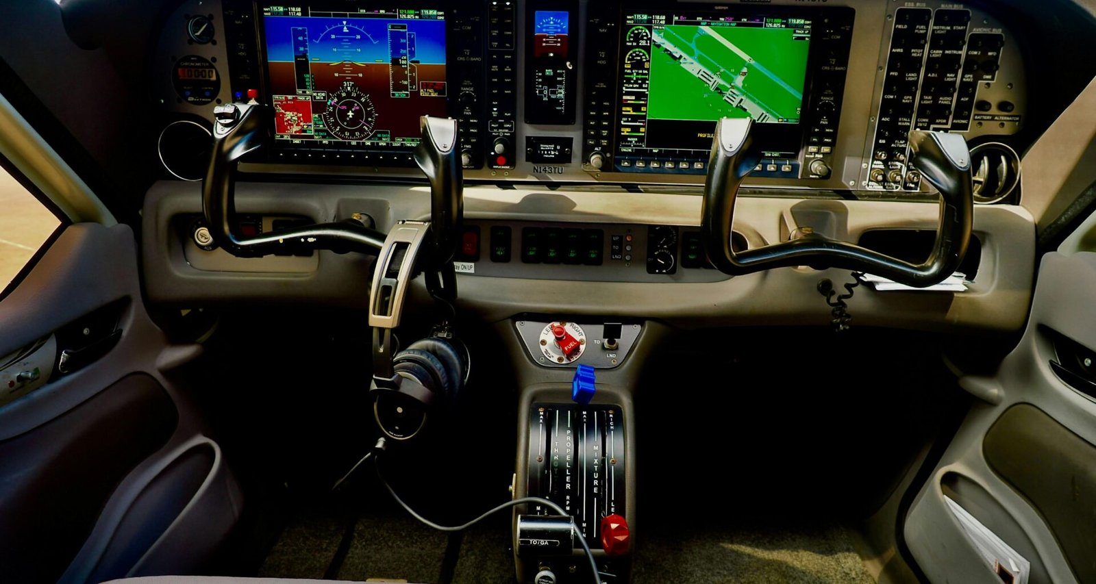 Modernes Flugzeugcockpit mit digitalen Anzeigen und Steuerungen, Fokus auf die technische Ausstattung im Cockpitbereich.
