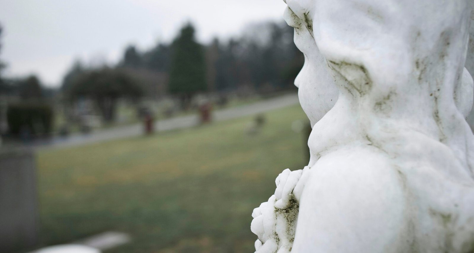 Nahaufnahme einer filigran gearbeiteten Marmor-Engelsstatue auf einem Friedhof, fotografiert von Leo_Visions