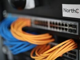 Detailaufnahme einer Netzwerk Switch Box mit sichtbaren Ports und Kabeln, symbolisiert moderne Netzwerktechnologien