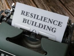 Nahaufnahme einer Schreibmaschine mit Papier, auf dem 'resilience building' steht – Symbol für Motivation im Arbeitsumfeld