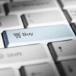 Nahaufnahme einer Computertastatur mit hervorgehobener buy-Taste, stellvertretend für Online-Shopping