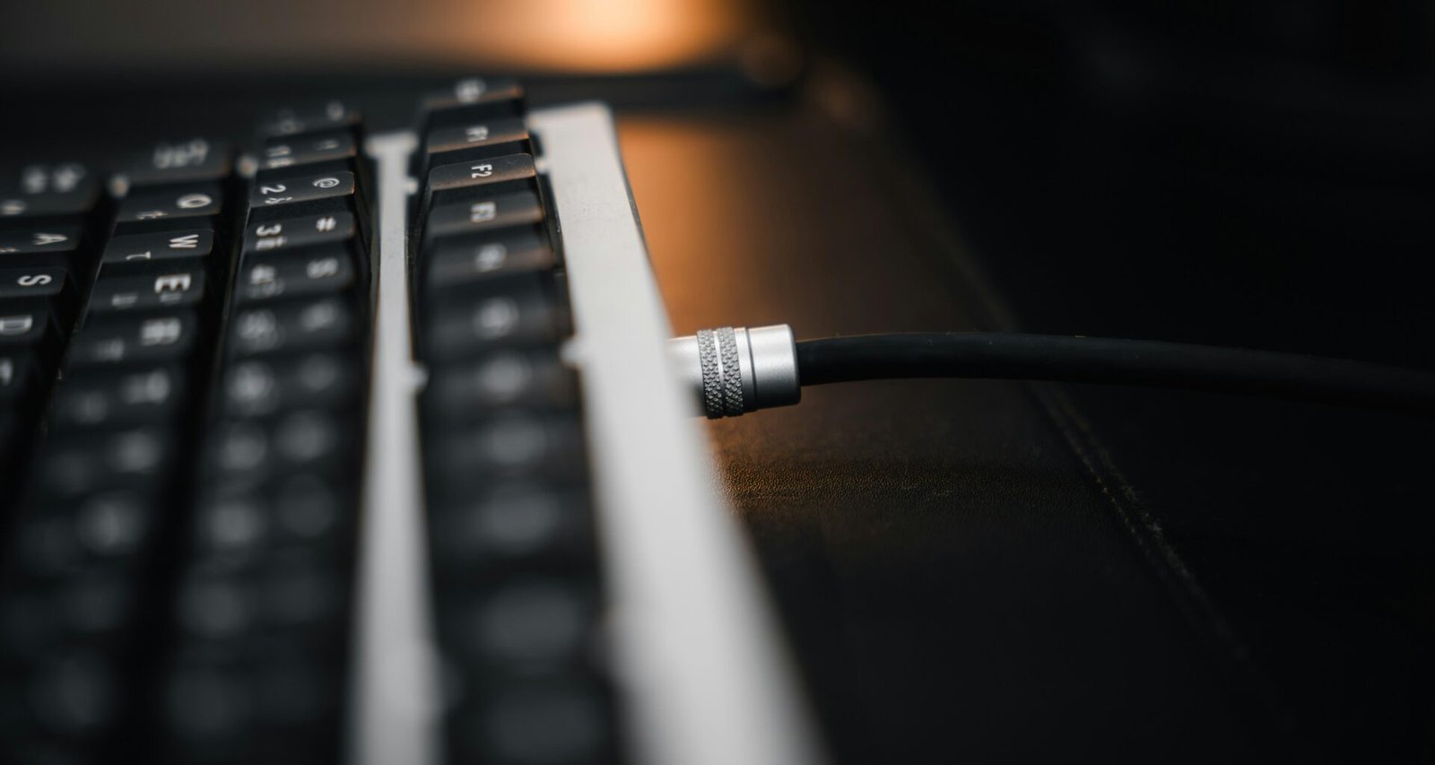 Nahaufnahme einer Computer-Tastatur mit angeschlossenem Kabel, ideal für Technik- und Online-Themen