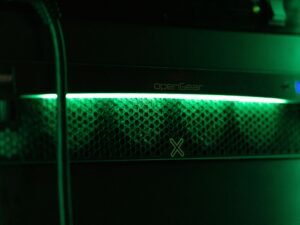 Nahaufnahme einer grünen Kontrollleuchte an einem Server in einem Rechenzentrum mit Fokus auf technische Details