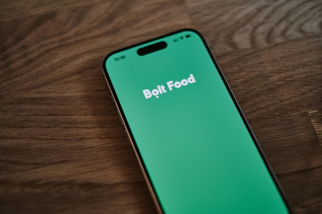 Nahaufnahme eines Smartphones, das auf einem Holztisch liegt. Fokus auf das Gerät und seine Position auf der Tischplatte.