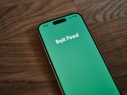 Nahaufnahme eines Smartphones, das auf einem Holztisch liegt. Fokus auf das Gerät und seine Position auf der Tischplatte.