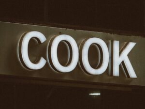 Nahaufnahme eines Schildes mit der Aufschrift Cook, aufgenommen von Jon Tyson, ideal für Artikel über Kochen oder Gastronomie.
