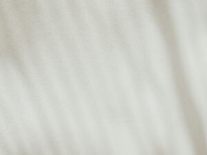 Makroaufnahme eines weißen Stoffes, bei der die Textur und feinen Fasern deutlich sichtbar sind