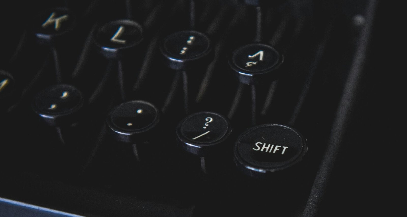 Detailansicht von klassischen Schreibmaschinentasten mit Fokus auf das Tastaturlayout vor schwarzem Hintergrund