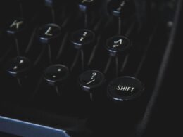 Nahaufnahme von schwarzen Vintage-Schreibmaschinentasten vor dunklem Hintergrund, Fokus auf Details der Typenmechanik.