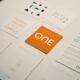 Orange Karte mit dem Aufdruck „one“ liegt mittig, umgeben von anderen bunt gemischten Karten auf einem Tisch.