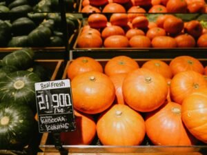 Mehrere orangefarbene Kürbisse liegen auf einer braunen Holzkiste, arrangiert für eine herbstliche Fotografie.