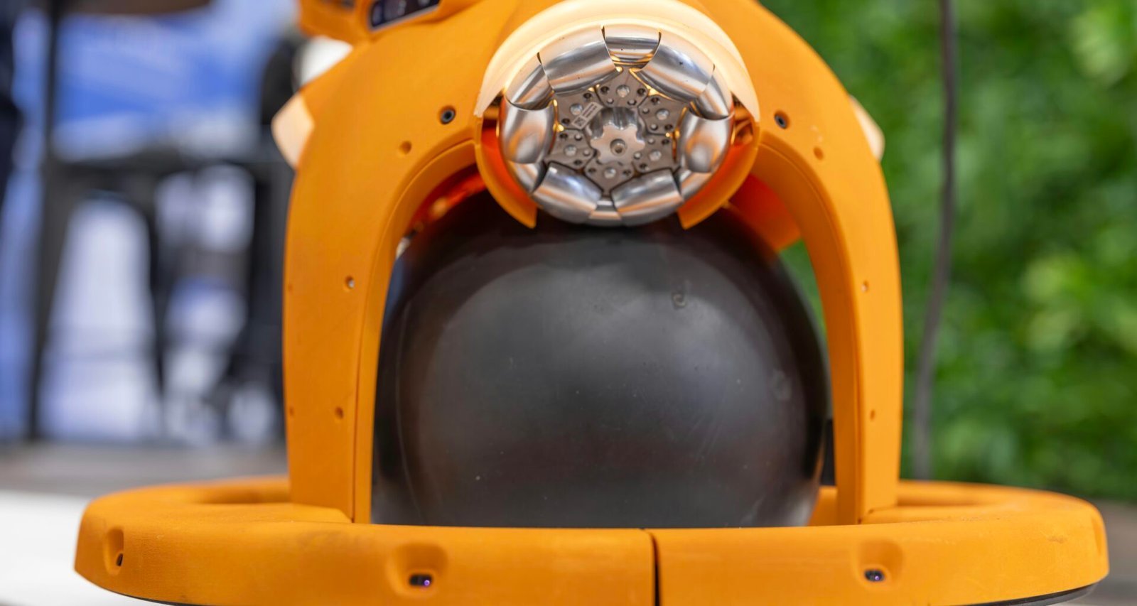 Orangefarbener Roboter mit schwarzen, kugelförmigen Elementen zeigt innovative Technologie in der Robotik.