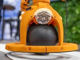 Orangefarbener Roboter mit schwarzen, kugelförmigen Elementen zeigt innovative Technologie in der Robotik.