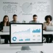Modernes High-Tech Büro mit digitalem Dashboard, Mitarbeitenden an Laptops und Whiteboard mit Skizzen zu Automatisierung und Content-Strategien