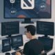 Moderner digitaler Arbeitsplatz mit mehreren Bildschirmen, Code, JSON-Feeds und Mediengraphen, im Hintergrund eine Darstellung des Apple News-Ökosystems mit HTML5, AMP und API-Integrationen