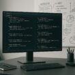 Moderner Webentwickler-Arbeitsplatz mit großem Monitor, Code-Editor und Whiteboard im Hintergrund