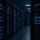 Innenaufnahme eines modernen Rechenzentrums mit blauen LED-Lichtern, geordneten Kabeln und Bildschirmen mit Netzwerkmessungen