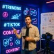 Junger Mann in Casual Fashion vor LED-Displays mit TikTok-Hashtags und Content-Analysen, im Hintergrund Whiteboards und Kamera, energiegeladene Atmosphäre im modernen Content-Studio