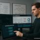 Geschäftsmann arbeitet an Touchscreen in einem High-Tech-Büro mit Monitoren, Whiteboards und digitalen Dashboards zur SEO-Optimierung.
