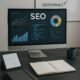 Moderner Arbeitsplatz mit Computermonitor, SEO Dashboard, Notizbüchern, Tablet und Whiteboard mit SEO-Diagrammen