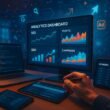 Nahaufnahme einer Hand mit Stylus oder Maus, die an einem großen Monitor mit Analytics, SEO- und SEM-Daten arbeitet, in einer High-Tech-Büroumgebung.