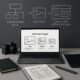 Moderner Arbeitsplatz mit Laptop, Kamera, Grafiktablett und Notizbuch, im Hintergrund schematische Diagramme zu SEO-Strategien, sauber und professionell gestaltet.