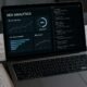Nahaufnahme eines modernen Laptops mit SEO-Analyse-Dashboards, Diagrammen und Codeseiten, umgeben von Checklisten und technischen Schaltplänen auf einem Schreibtisch