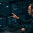 Moderner High-Tech-Arbeitsplatz mit Monitoren, Datenanalysen, Code, Netzwerkdiagrammen und einem Serverraum im Hintergrund. Credit: 404 Magazine (Tobias Hager)