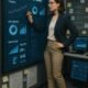 Professionelle Frau in Business-Outfit analysiert digitale SEO-Daten und Diagramme vor einer großen Tafel, im Hintergrund Projektboards und Computerbildschirme