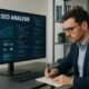 Technisches Büro mit großem Bildschirm, der eine SEO-Analysetafel mit Diagrammen und Code-Editoren zeigt. Im Vordergrund sitzt ein Entwickler in Business-Casual, im Hintergrund Regale mit technischen Büchern und Servergeräte.