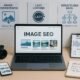 Modernes digitales Arbeitszimmer mit Laptop, Kamera, Smartphone und Infografiken zur Bild-SEO-Optimierung, helles und technisch inspiriertes Setting
