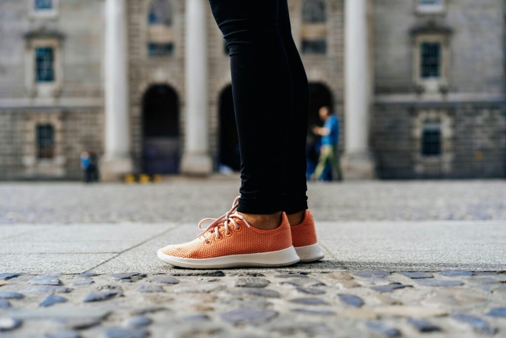 Ein Paar orangefarbene Low-Top-Schuhe auf hellem Untergrund, minimalistisch inszeniert, Fokus auf Farbe und Form