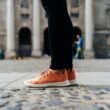 Ein Paar orangefarbene Low-Top-Schuhe auf hellem Untergrund, minimalistisch inszeniert, Fokus auf Farbe und Form