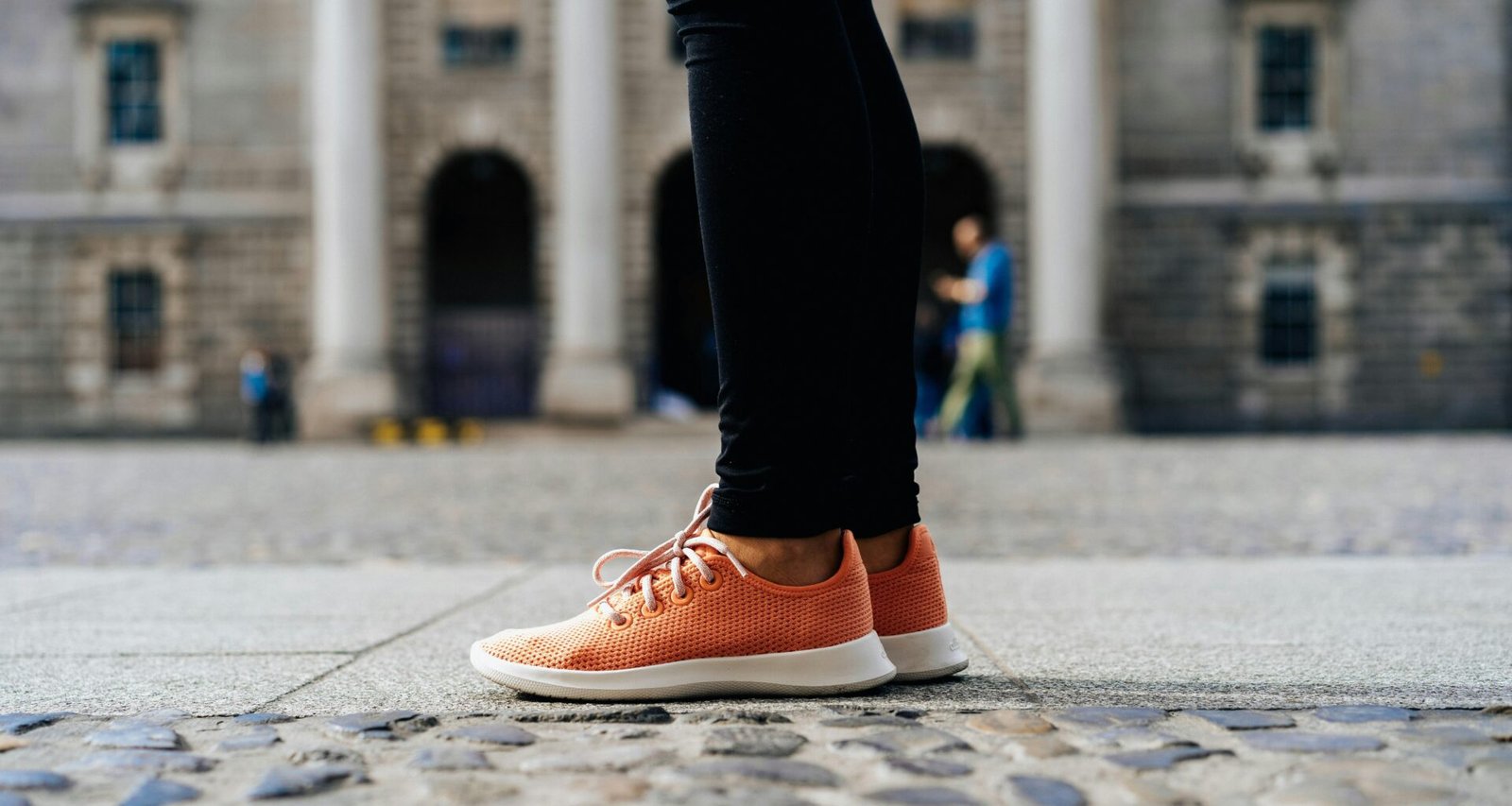 Ein Paar orangefarbene Low-Top-Schuhe auf hellem Untergrund, minimalistisch inszeniert, Fokus auf Farbe und Form